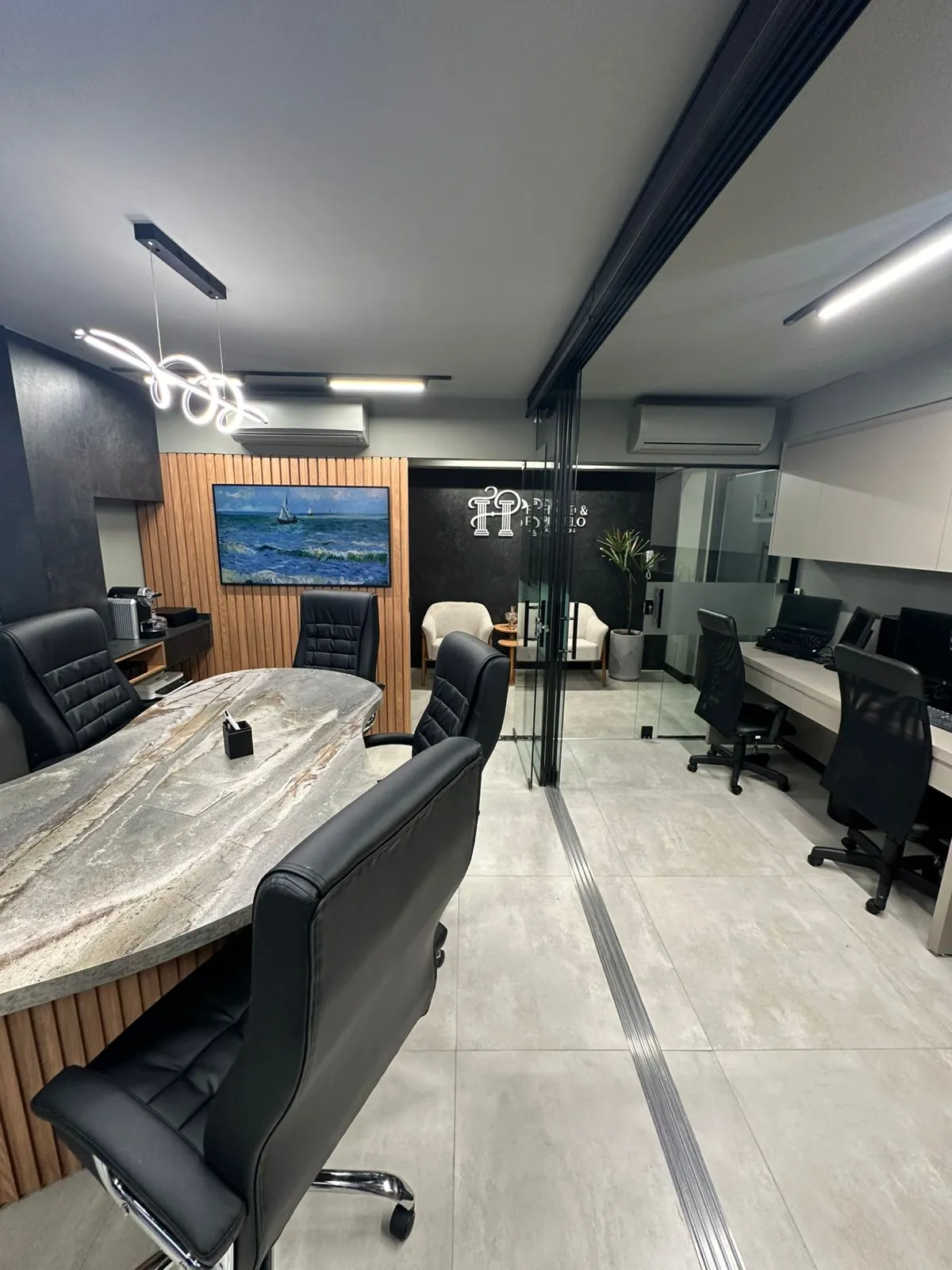 Sala de reunião do escritório Fidalgo & Pustrelo — mesa de mármore, painéis de madeira e logo ao fundo